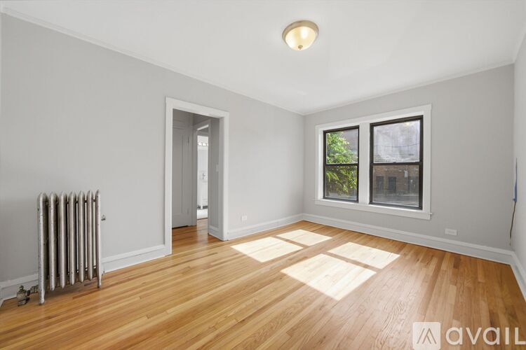 A room with wooden floors and a window with a view of trees.