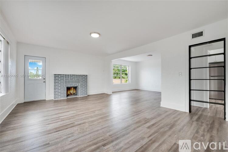 A spacious living room with a fireplace and a large window.