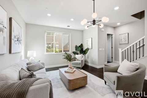 A living room with a grey couch, a coffee table, and a chandelier.