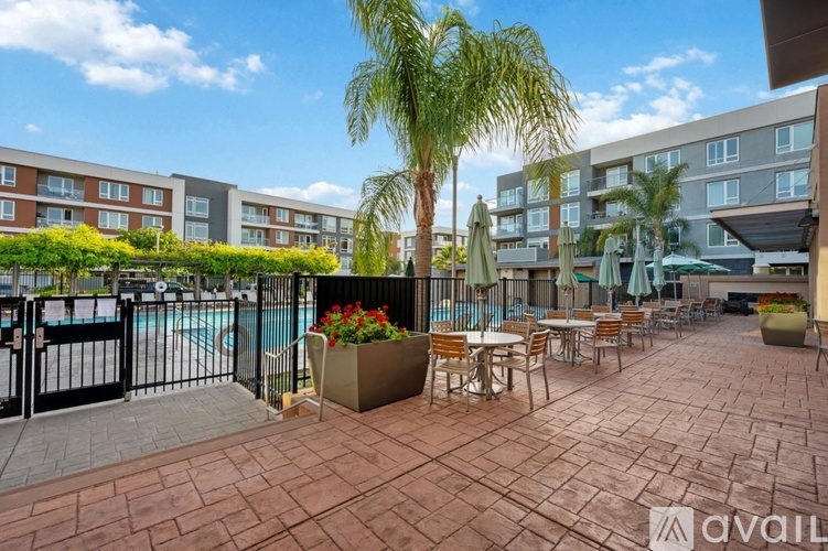 A patio area with tables and chairs and a pool in the background.