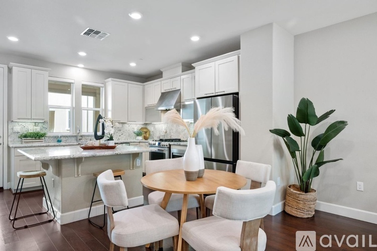 A modern kitchen with a dining table set up with chairs.
