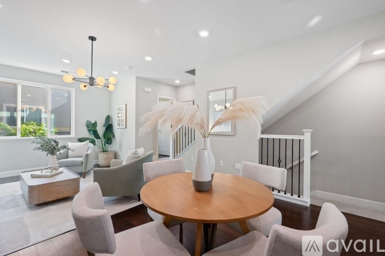 A modern living room with a wooden table and white chairs.