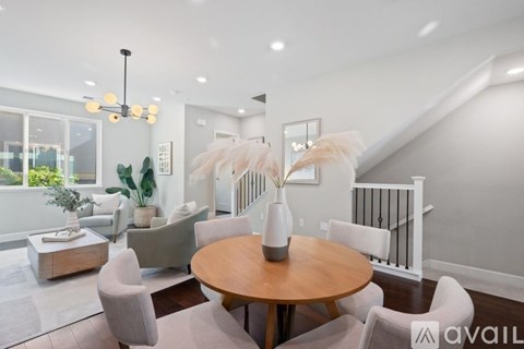 A modern living room with a wooden table and white chairs.