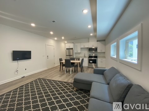 A living room with a grey sofa and a black and white patterned rug.