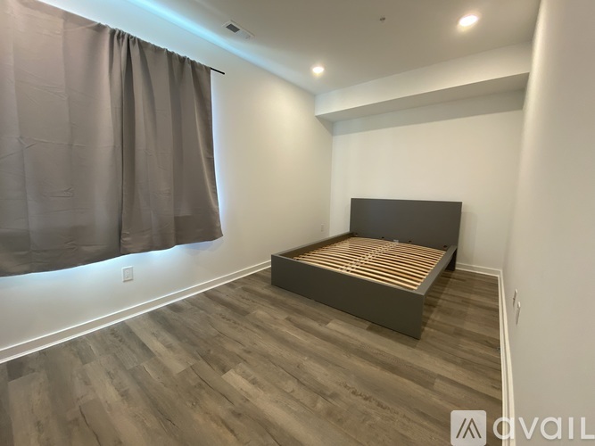 A bedroom with a bed and wooden flooring.