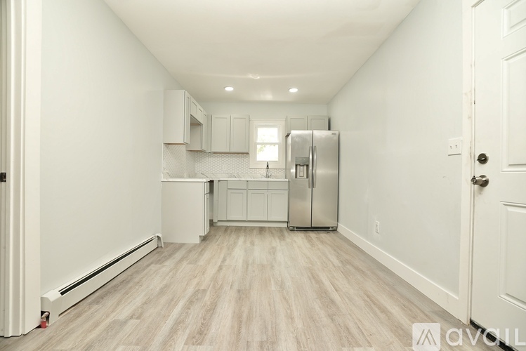 A white kitchen with wood flooring and stainless steel appliances.