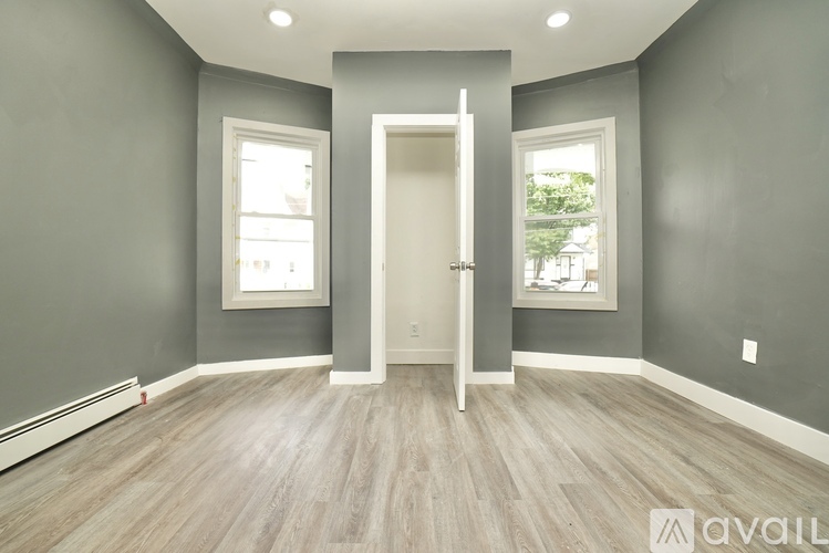 A room with grey walls and wooden flooring with a white door in the middle.