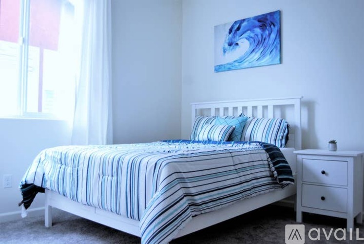 A bedroom with a white bed and a blue and white striped comforter.