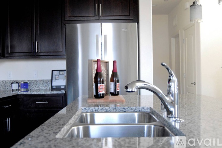 A kitchen with a stainless steel refrigerator and a granite countertop.