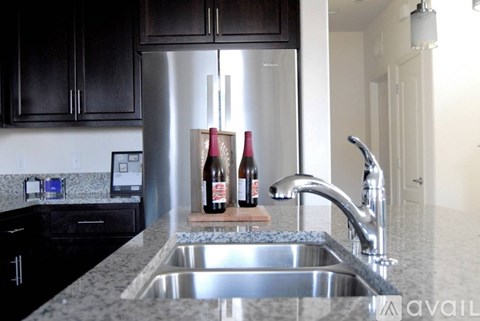 A kitchen with a stainless steel refrigerator and a granite countertop.