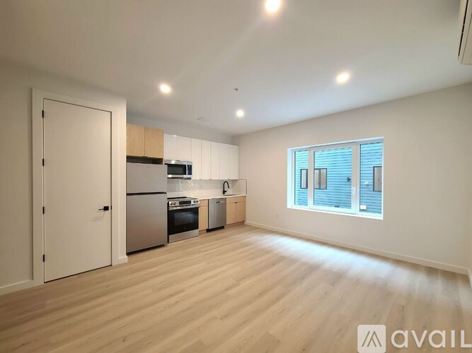 A spacious kitchen with wooden floors and a window with blinds.
