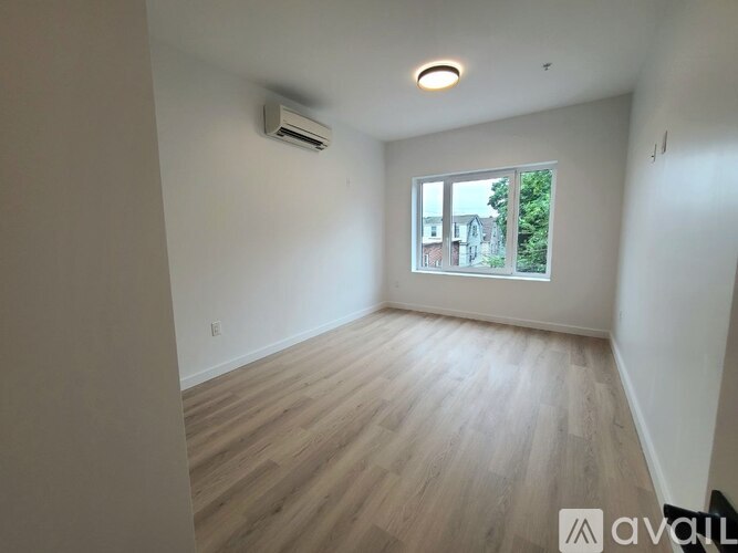 A room with wooden flooring and a window showing a view of buildings and trees outside.