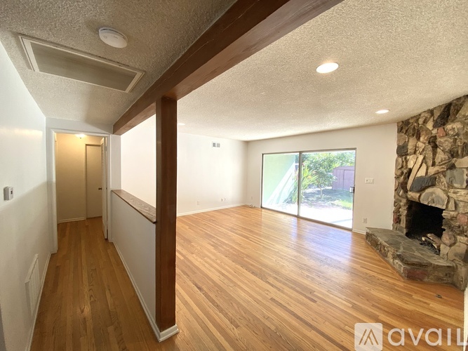 A living room with a stone fireplace and wood flooring.
