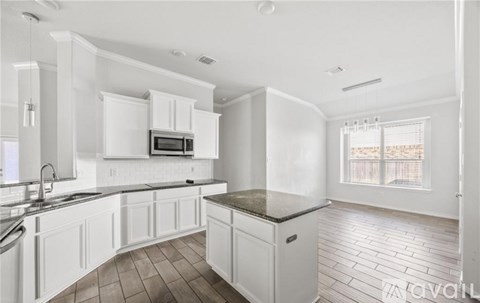 A kitchen with white cabinets and a black countertop.