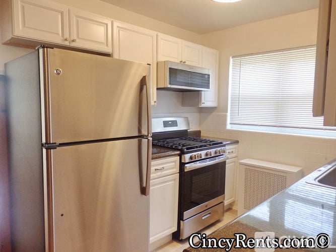 A kitchen with a stainless steel refrigerator and a stove top oven.