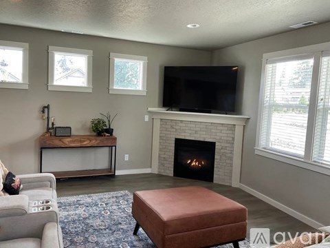 A living room with a fireplace and a television on the wall.