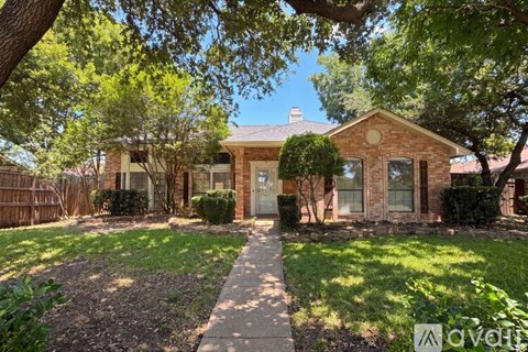 A house with a brick facade is surrounded by a well-kept lawn and trees.