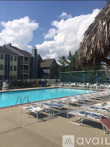 A pool with sun loungers and a thatched roof building in the background.