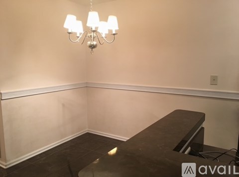 A room with a chandelier, a bench, and a wall with a baseboard.