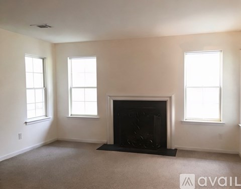A living room with a fireplace and two windows.