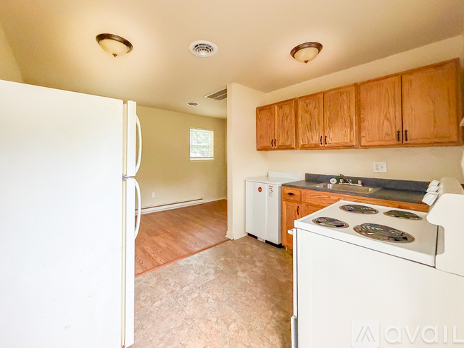 A kitchen with a white refrigerator, stove, and cabinets.