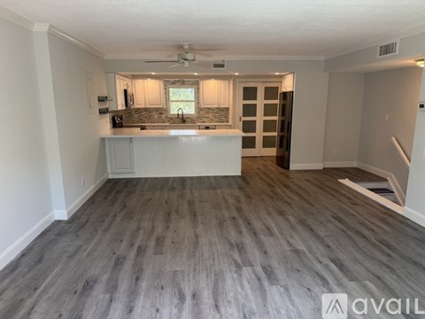 A spacious room with a kitchenette and a staircase.