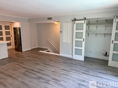 A room with a grey floor and white walls, with a staircase leading to the upper level.
