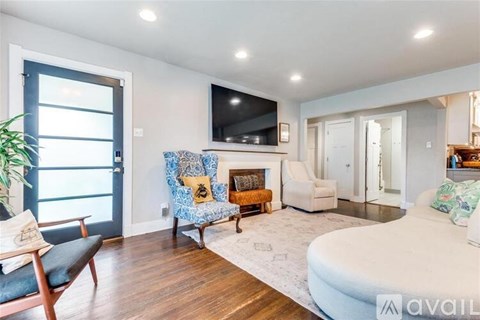 A living room with a blue chair and a fireplace.