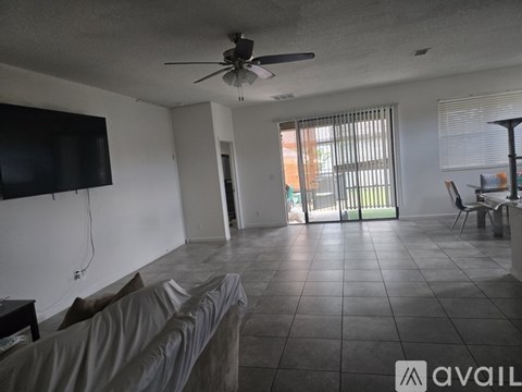 A living room with a grey couch and a flat screen TV mounted on the wall.