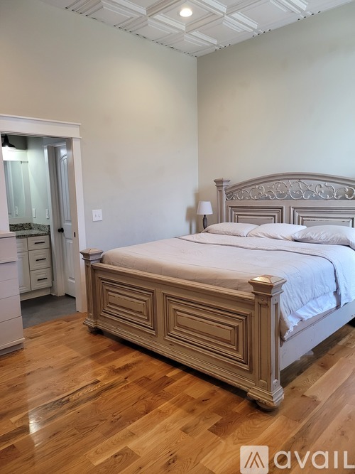 A bedroom with a large bed and wooden floors.