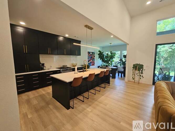 A modern kitchen with black cabinets and a white island.
