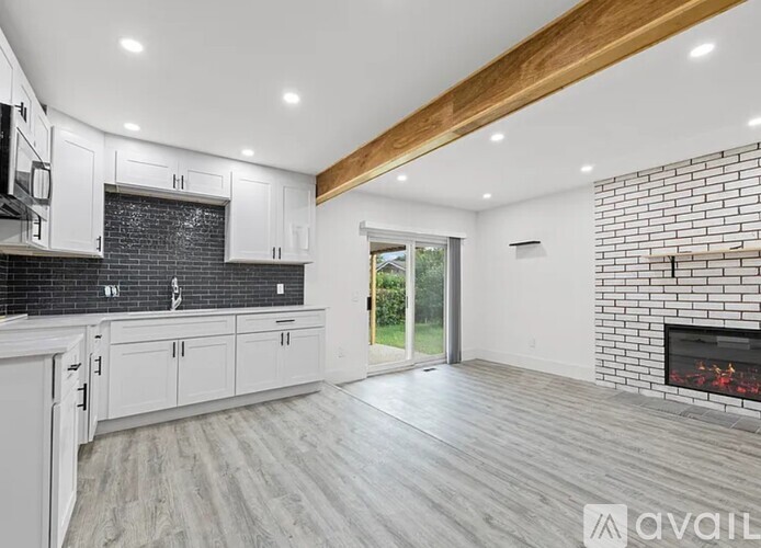 A modern kitchen with white cabinets and a brick accent wall.