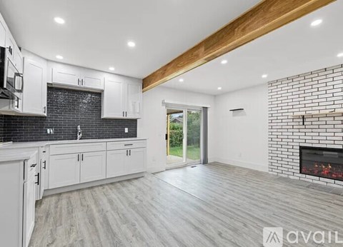 A modern kitchen with white cabinets and a brick accent wall.