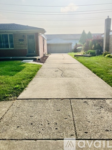 A concrete walkway leads to a house with a garage.