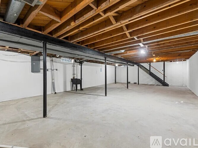 A spacious attic room with wooden beams and a concrete floor.
