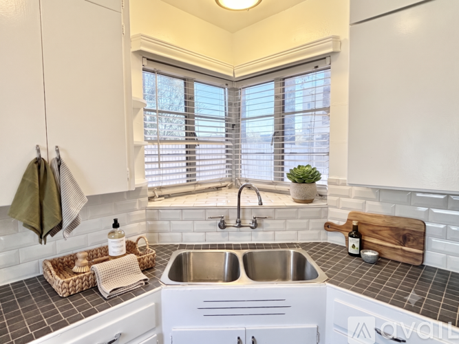 A kitchen with a white sink and a window with blinds.