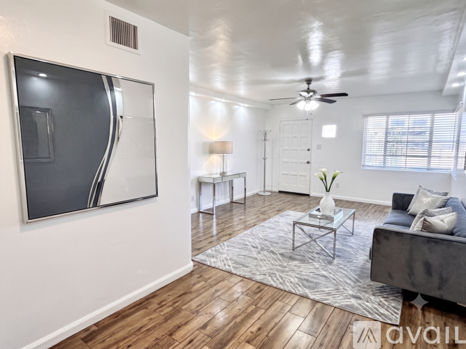 A modern living room with a grey couch, a coffee table, and a large abstract painting on the wall.
