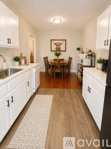 A kitchen with white cabinets and a wooden floor.