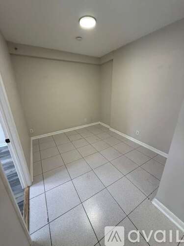 A room with white tiled flooring and a single light fixture on the ceiling.