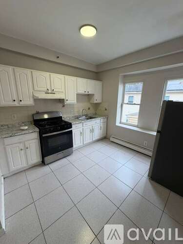 A kitchen with white cabinets and black appliances.