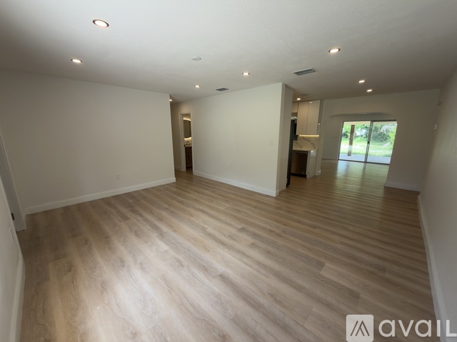 A spacious room with wooden flooring and white walls.