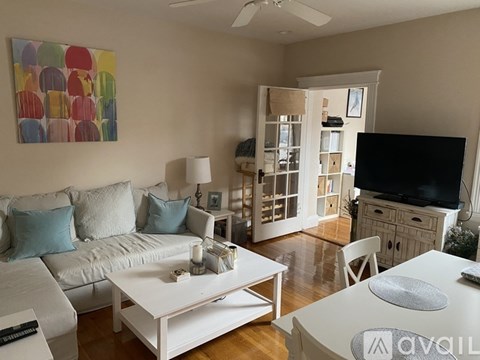 A living room with a white couch and a painting on the wall.