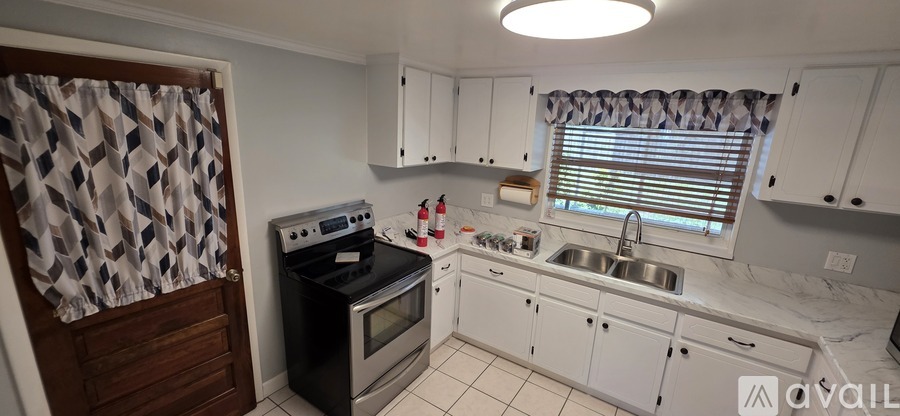 A kitchen with white cabinets and a black stove top oven.