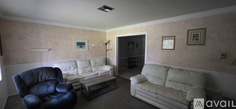 A living room with a black leather chair and a white sofa.