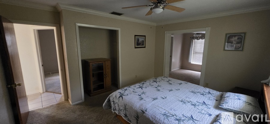 A bedroom with a bed, a ceiling fan, and a cabinet.