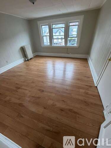 A room with wooden flooring and a window overlooking a street.