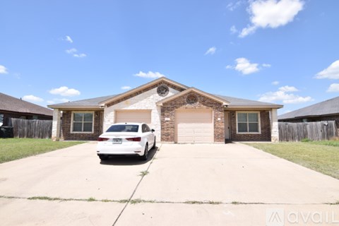 A white car is parked in front of a house with a garage.