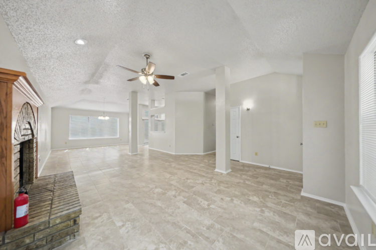 A spacious living room with a fireplace and a fan on the ceiling.