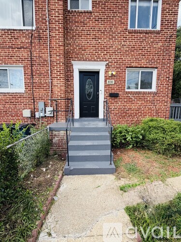 A brick building with a black door and a small front yard.