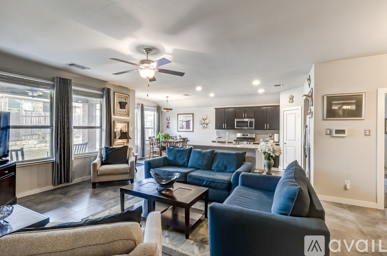 A living room with a blue couch and a fan on the ceiling.